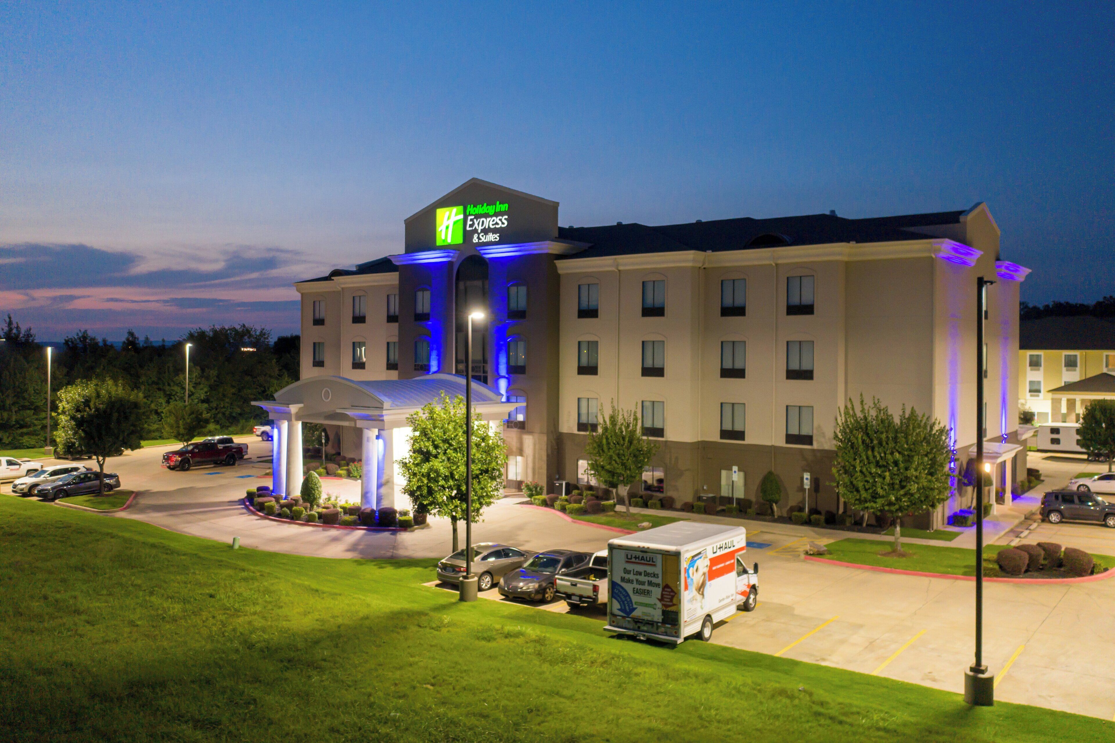 Un hotel Holiday Inn Express & Suites con un estacionamiento y una camioneta U-Haul.