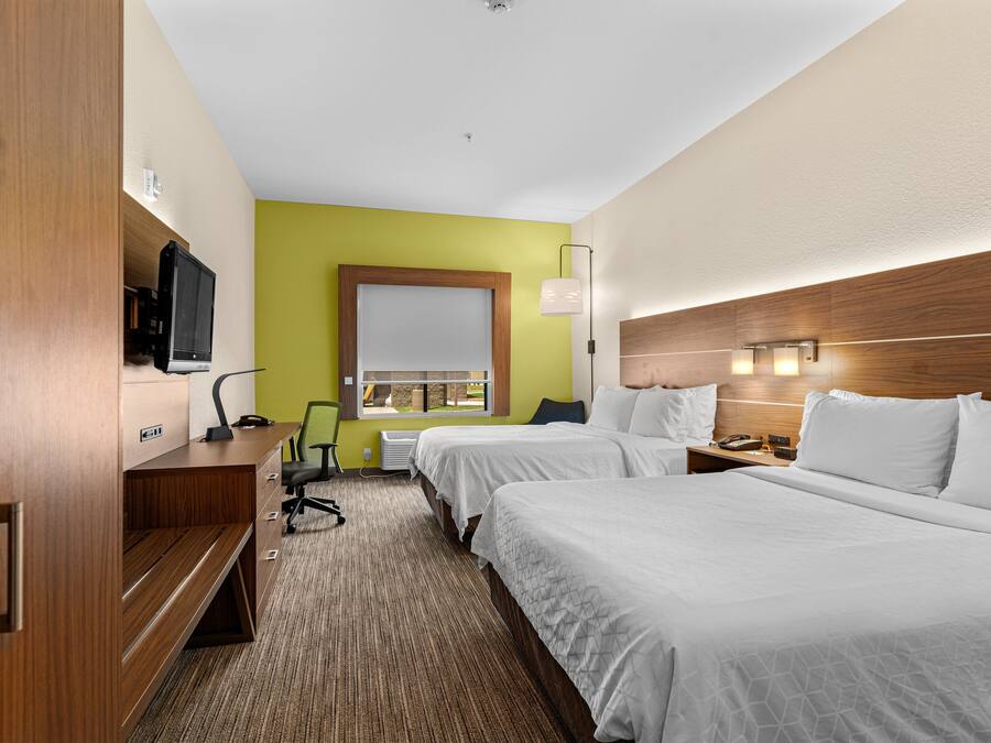 A hotel room with two beds, a desk with a computer, a TV, and a window with a view.