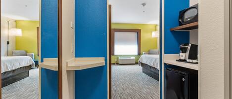 Habitación de hotel con dos camas, microondas, cafetera y un refrigerador pequeño.
