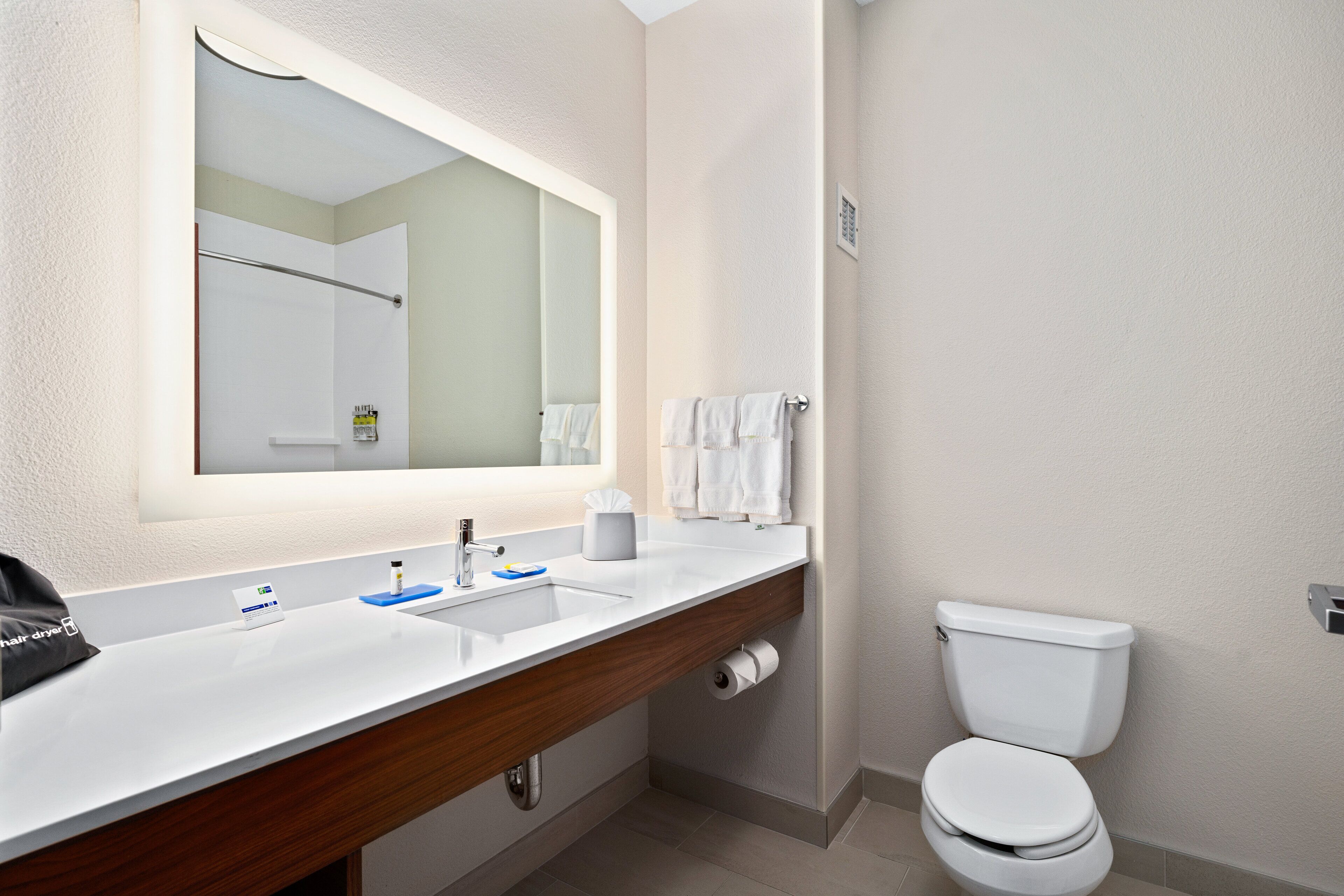 A bathroom with a white sink, mirror, and toilet.