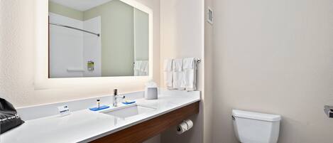 A bathroom with a white sink, mirror, and toilet.