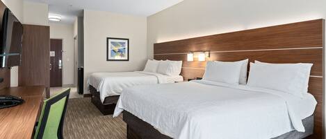 A hotel room with two beds, a desk, a chair, and a TV.