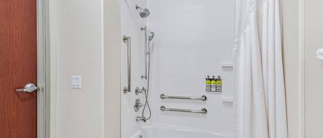 A bathroom with a shower, a bathtub, and a door with a wooden panel.