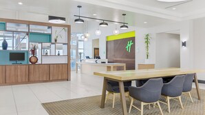 Un espace de bureau moderne comprenant un comptoir d’accueil, une longue table avec des chaises et un tapis à motifs.