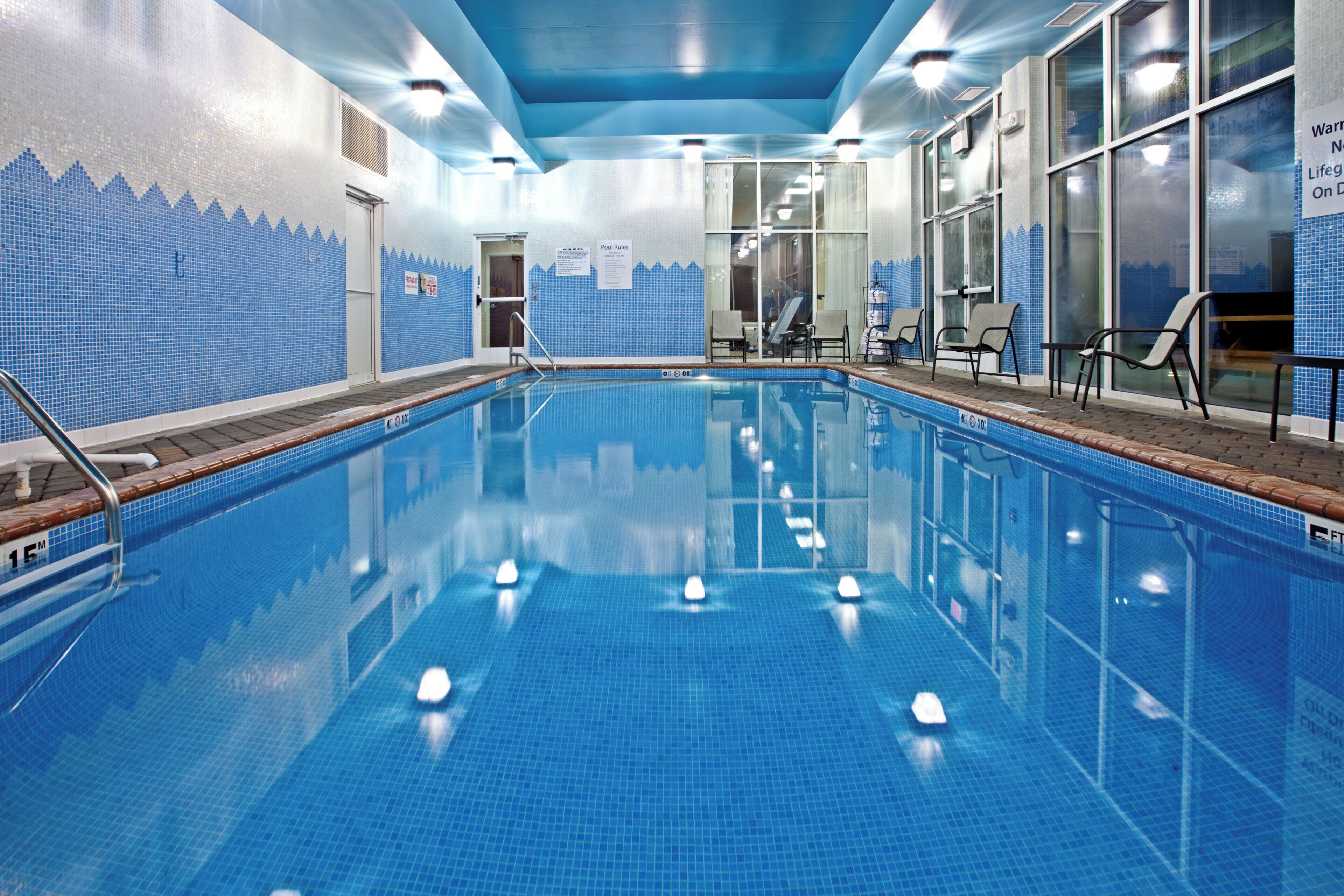 An indoor swimming pool with clear water, tiled walls, and a lifeguard chair.