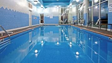 An indoor swimming pool with clear water, tiled walls, and a lifeguard chair.