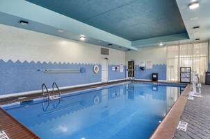 Una piscina interior con agua cristalina, paredes con azulejos y techo azul.