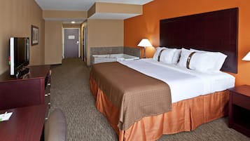 A hotel room with a bed, bedside tables, a TV, and a bathroom.