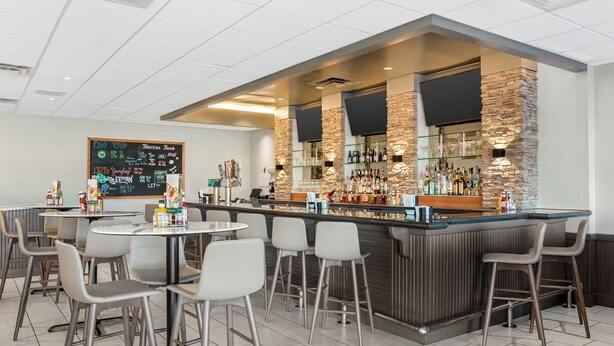Un espace bar moderne avec un mur d’accent en pierre, de nombreux types de sièges et un menu écrit à la craie.