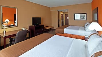 A hotel room with two beds, a desk, a television, and a mirror.