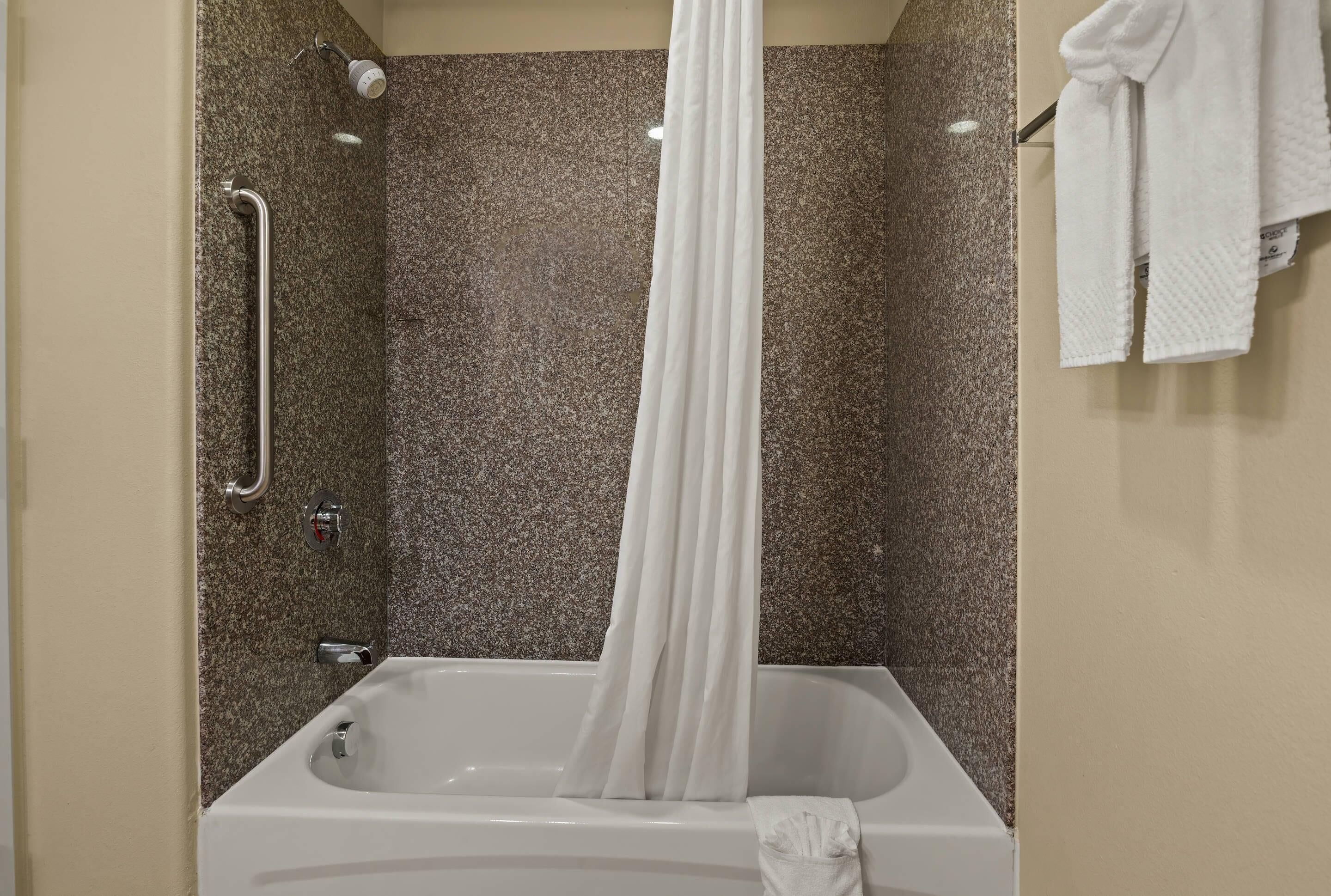 A bathroom with a bathtub, a shower, and a towel rack.