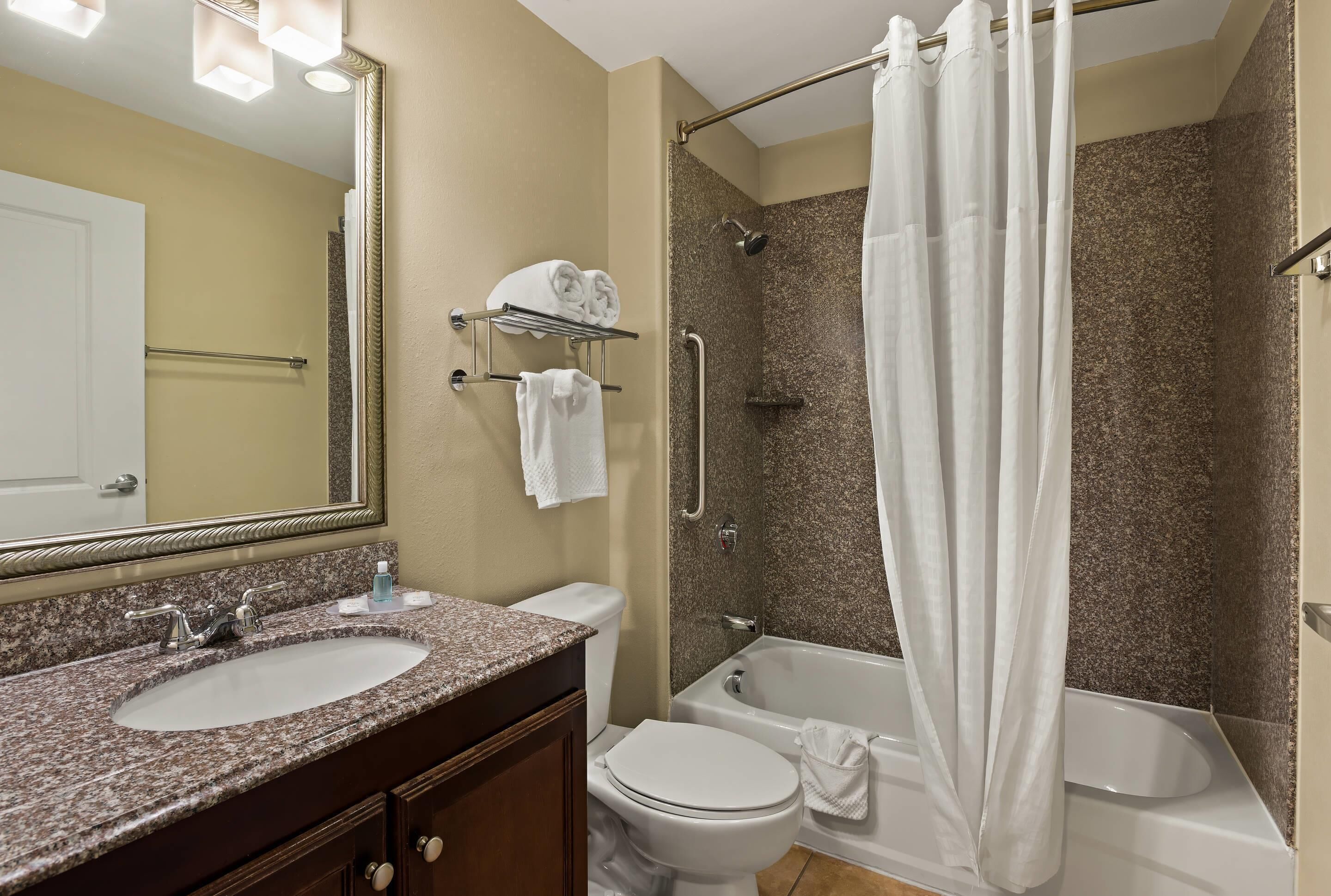 A bathroom with a double sink vanity, a toilet, a shower with a glass door, and a large mirror.