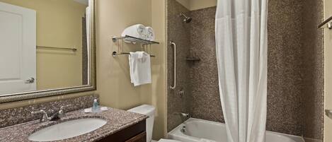 A bathroom with a double sink vanity, a toilet, a shower with a glass door, and a large mirror.