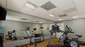 A gym with multiple exercise machines, a water dispenser, and a mirror reflecting the equipment. - MainStay Suites Houma (Houma)