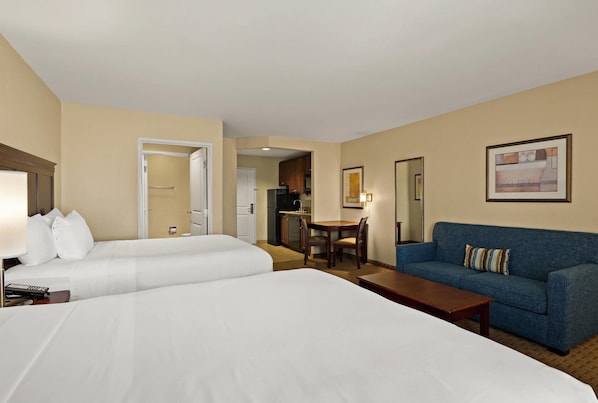 Une chambre d’hôtel avec deux lits, un canapé, une table à manger et un coin cuisine.