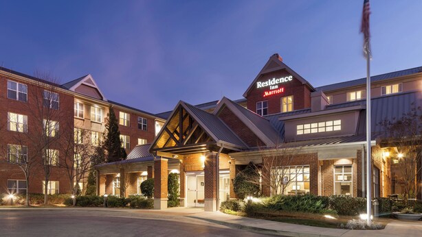 A brick building with a sign reading "Residence Inn Marriott" and a flagpole with an American flag.