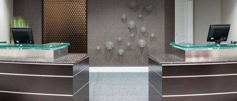 A reception area with two glass-top counters, a textured wall, and a patterned floor.