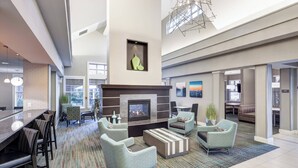 A spacious lobby with a fireplace, comfortable seating, and a bar area.