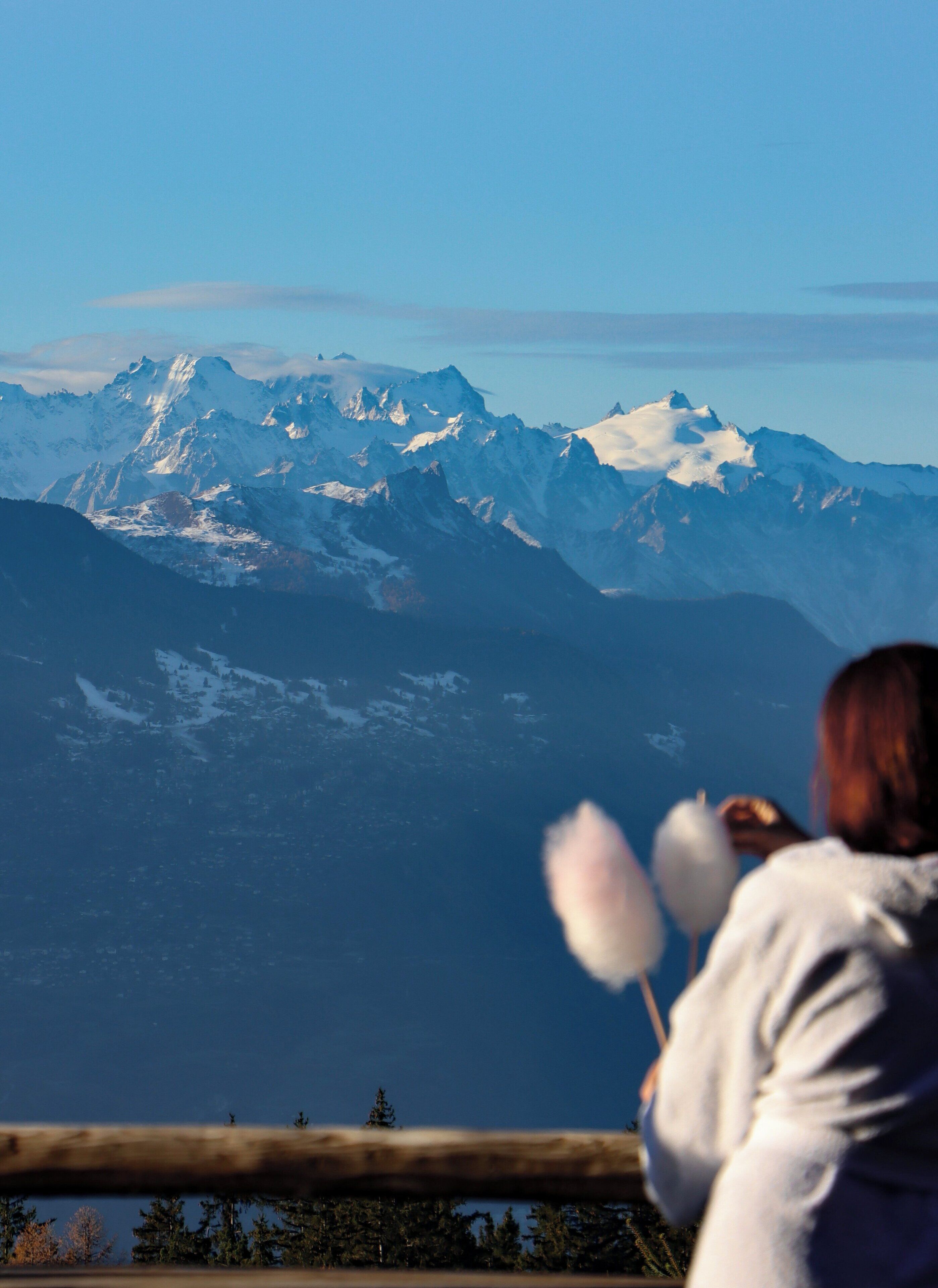 A person taking a photo of snow-covered mountains.