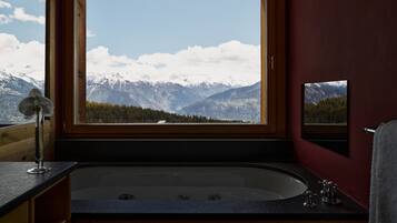 A bathroom with a large window, a bathtub, and a mirror.