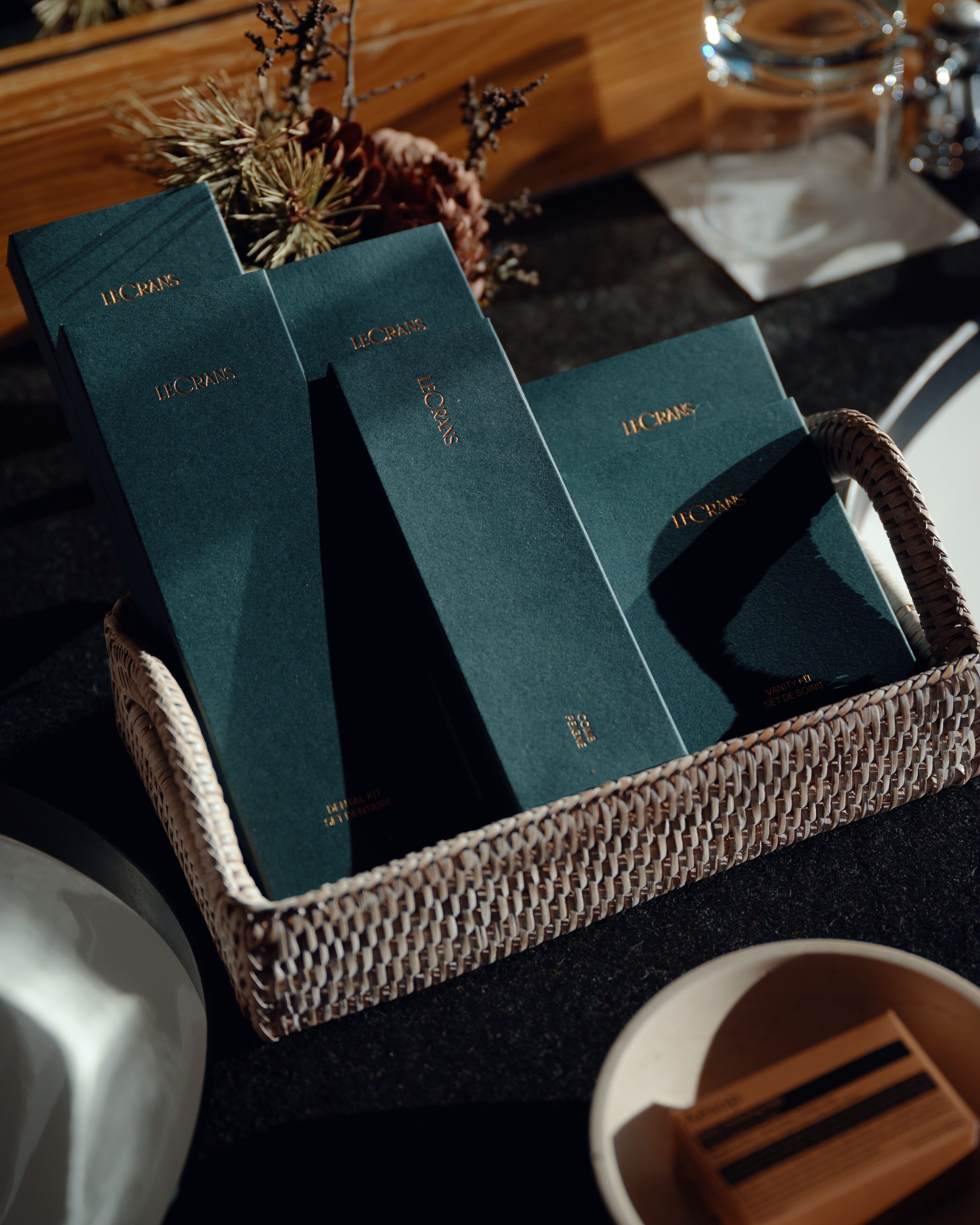 A wicker basket containing two dark green books with gold lettering, placed on a dark countertop.