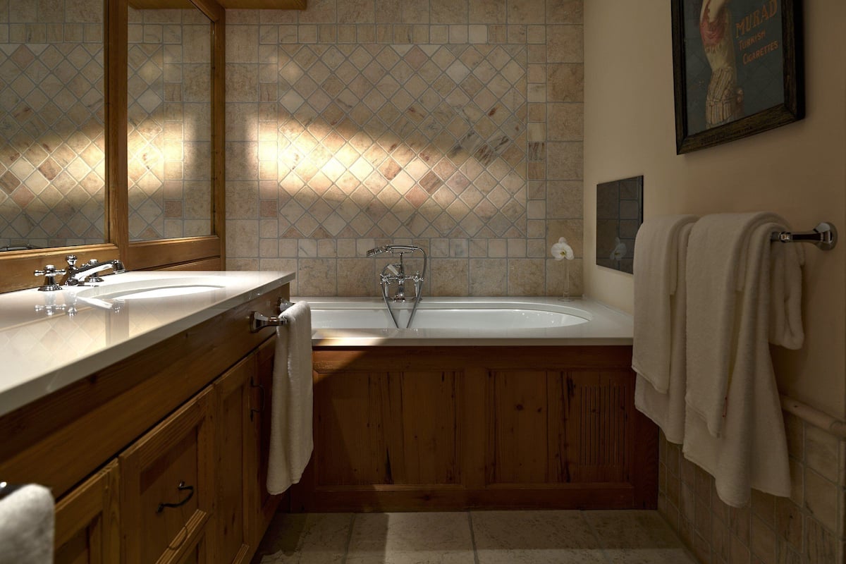 Une salle de bain avec deux lavabos, une baignoire, des meubles en bois et un mur carrelé.