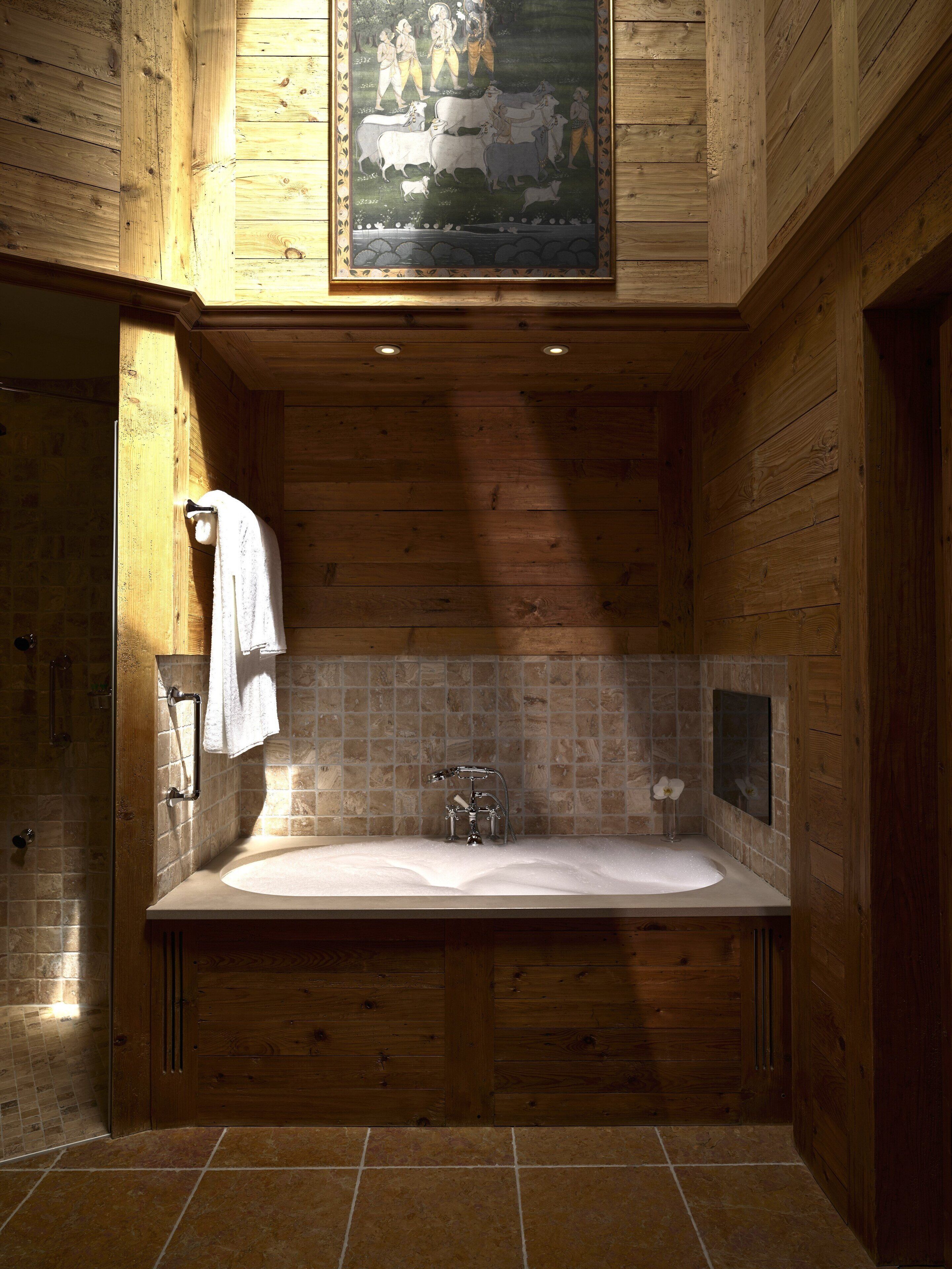 Un baño de madera con una bañera grande, ducha y pared con azulejos.