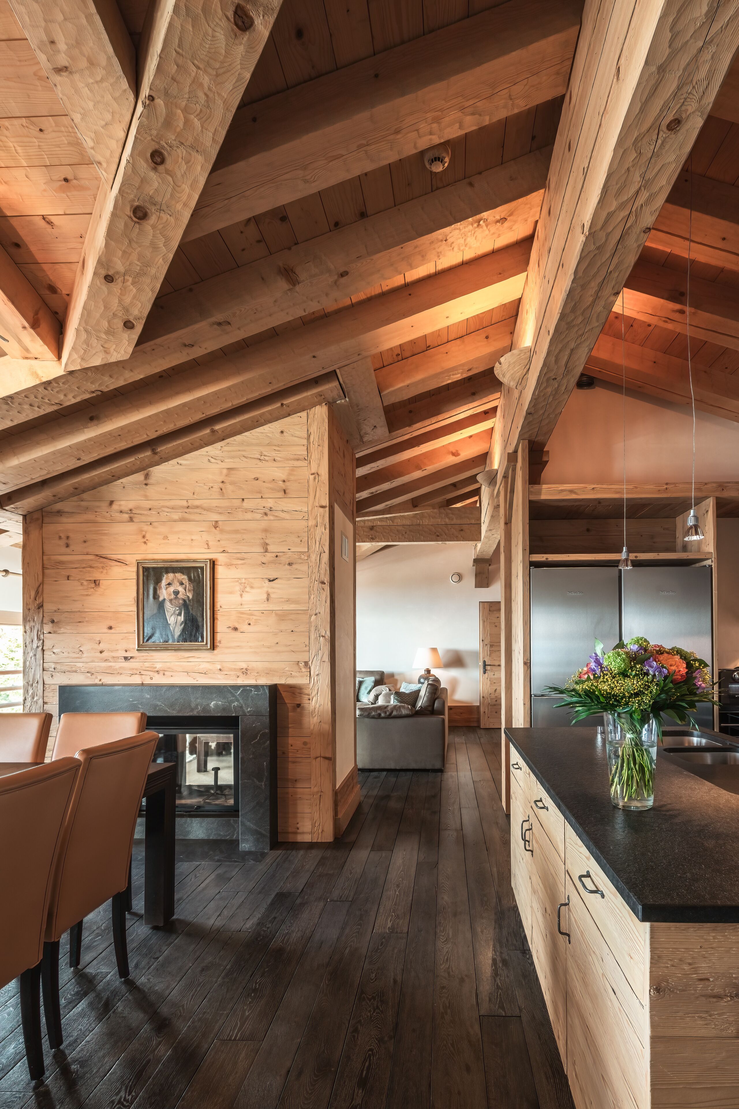 Una cocina moderna con vigas de madera, zona de comedor y chimenea.