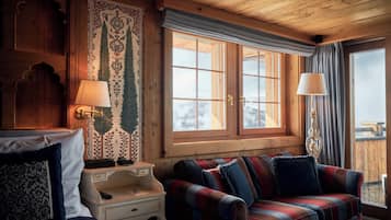 A cozy room with a plaid sofa, a wooden headboard, and a large window with curtains.