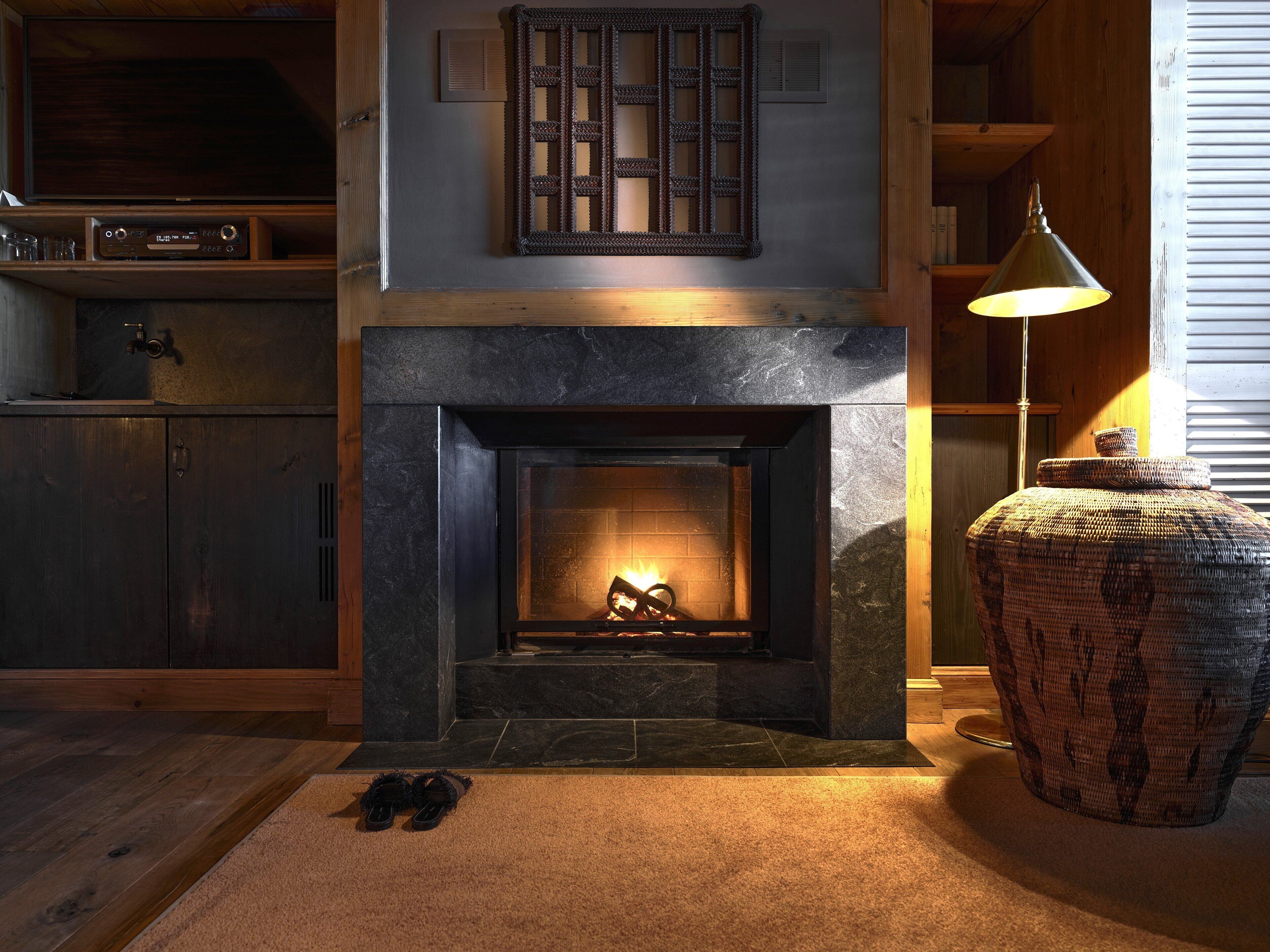 A cozy room with a fireplace, wooden flooring, and a large woven basket.