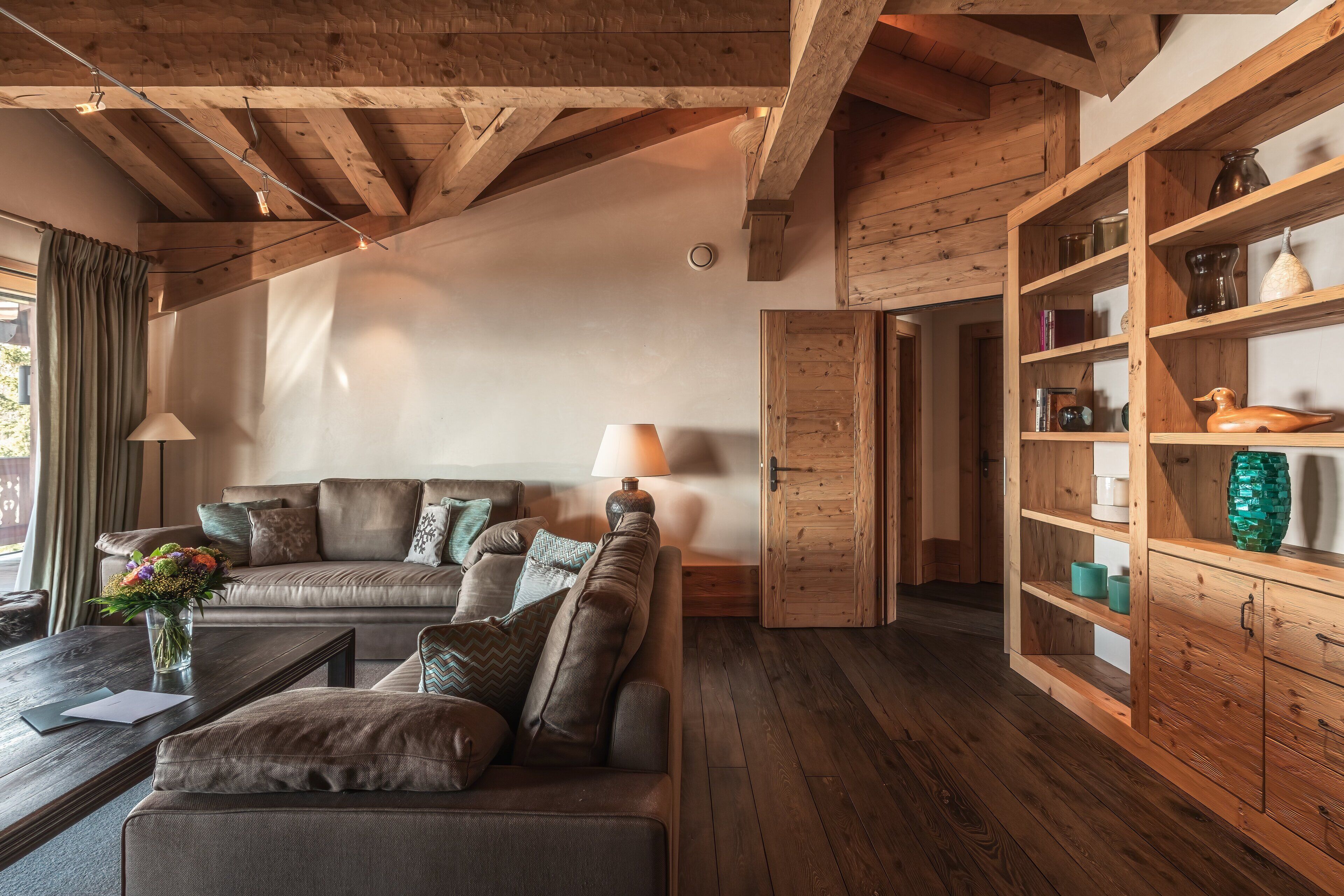 Una sala de estar acogedora con techo de madera, un sofá de cuero, una mesa de centro y un aparador de madera con estantes.