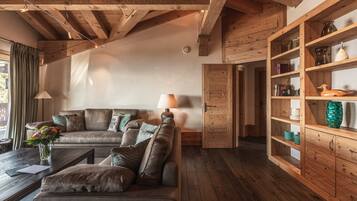 Una sala de estar acogedora con techo de madera, un sofá de cuero, una mesa de centro y un aparador de madera con estantes.