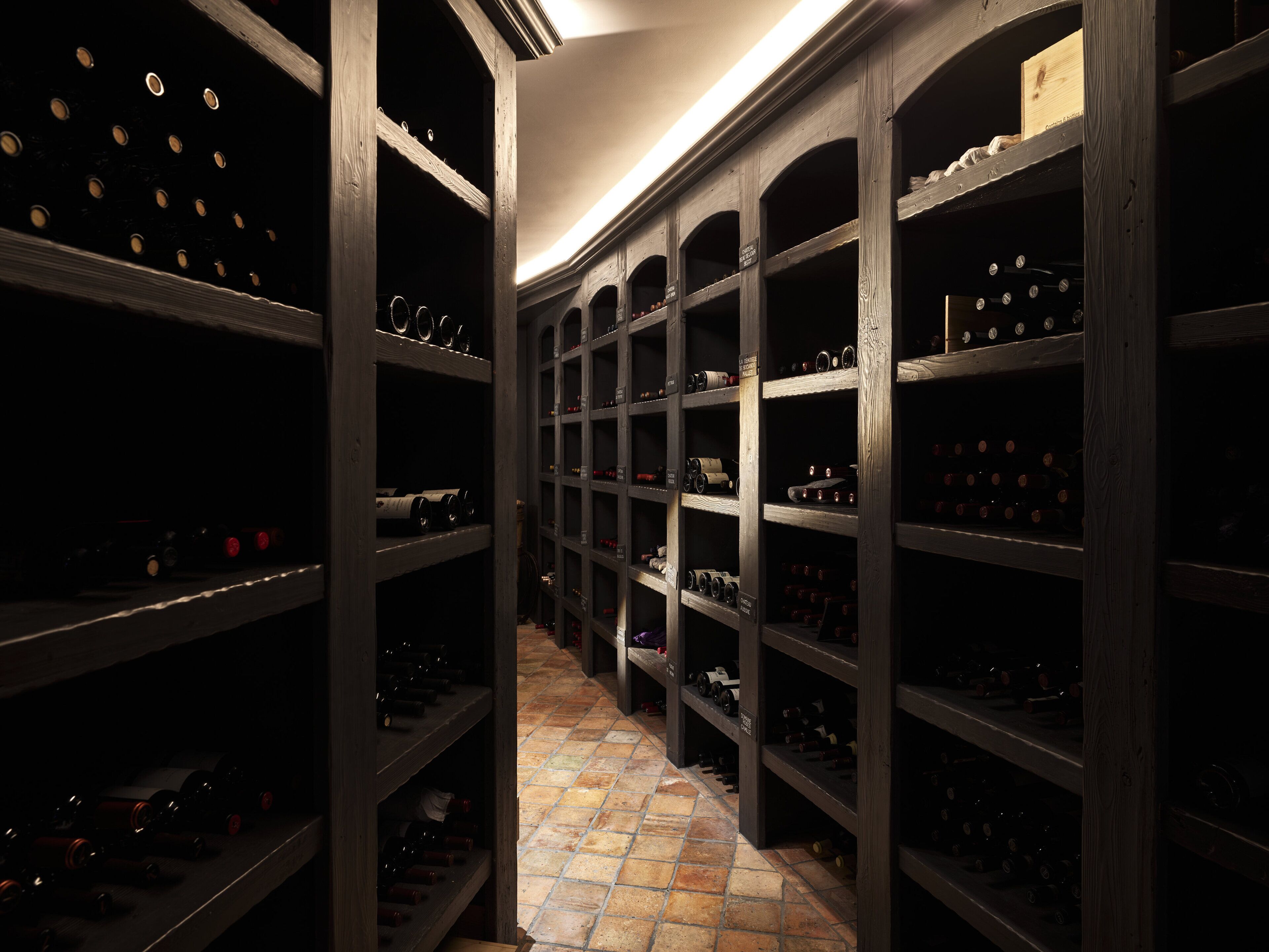 A wine cellar with wooden shelves and a tiled floor.