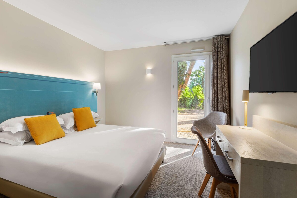 Une chambre d’hôtel avec un lit, un bureau, une chaise et un téléviseur.