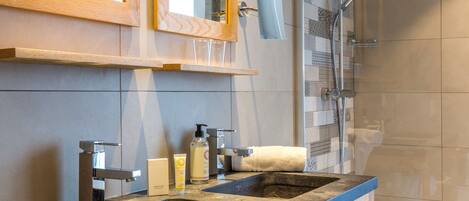 A bathroom with two sinks, a mirror, a towel rack, and a shower area.