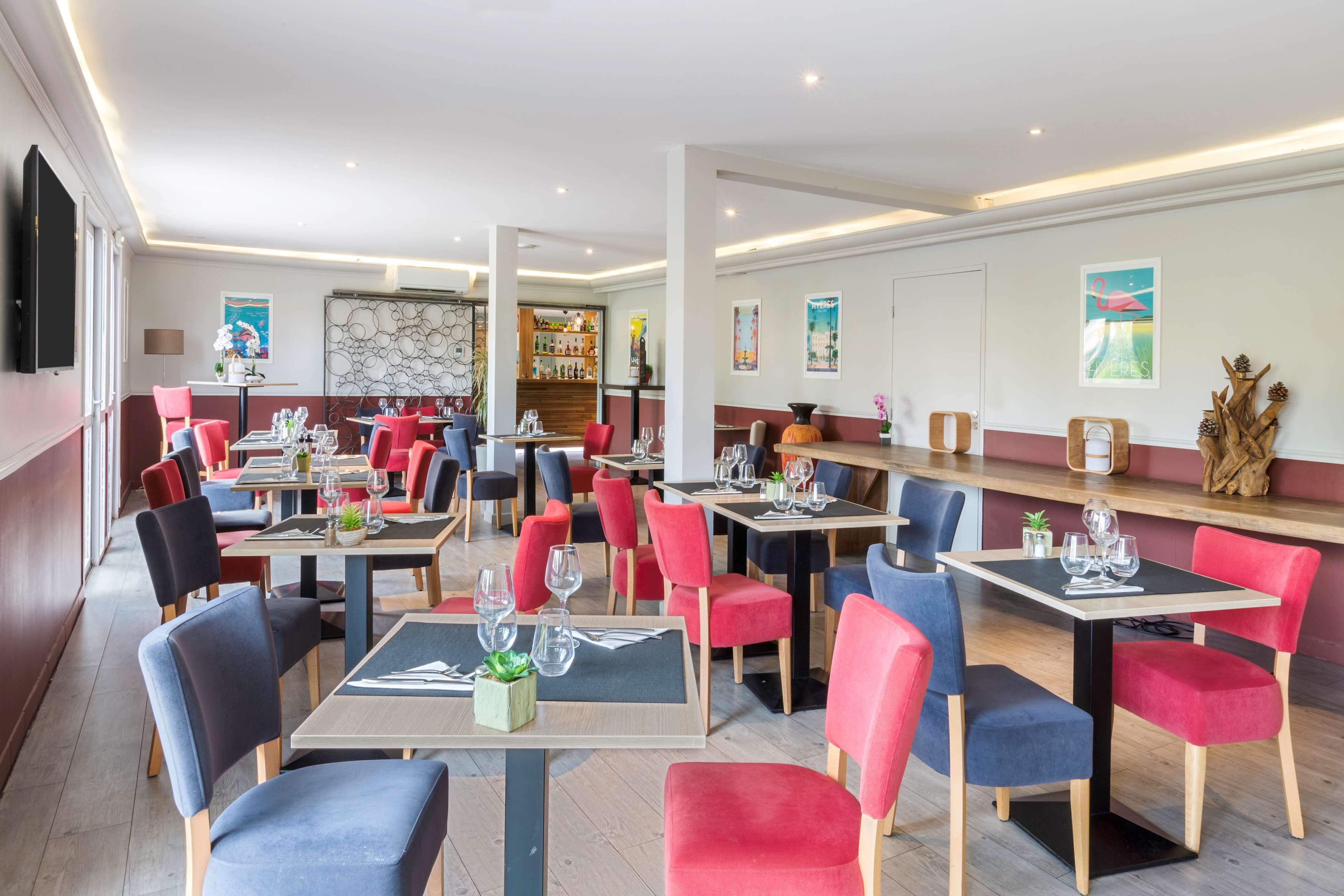 A modern restaurant with multiple tables and chairs, a bar area, and a variety of wall decorations.