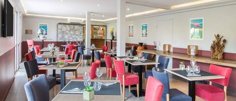 A modern restaurant with multiple tables and chairs, a bar area, and a variety of wall decorations.