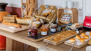 Un bufé de desayuno con panes, pasteles y mermeladas variadas.