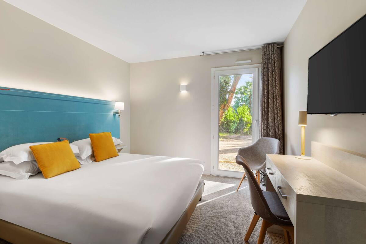 A hotel room with a bed, a desk, and a television.