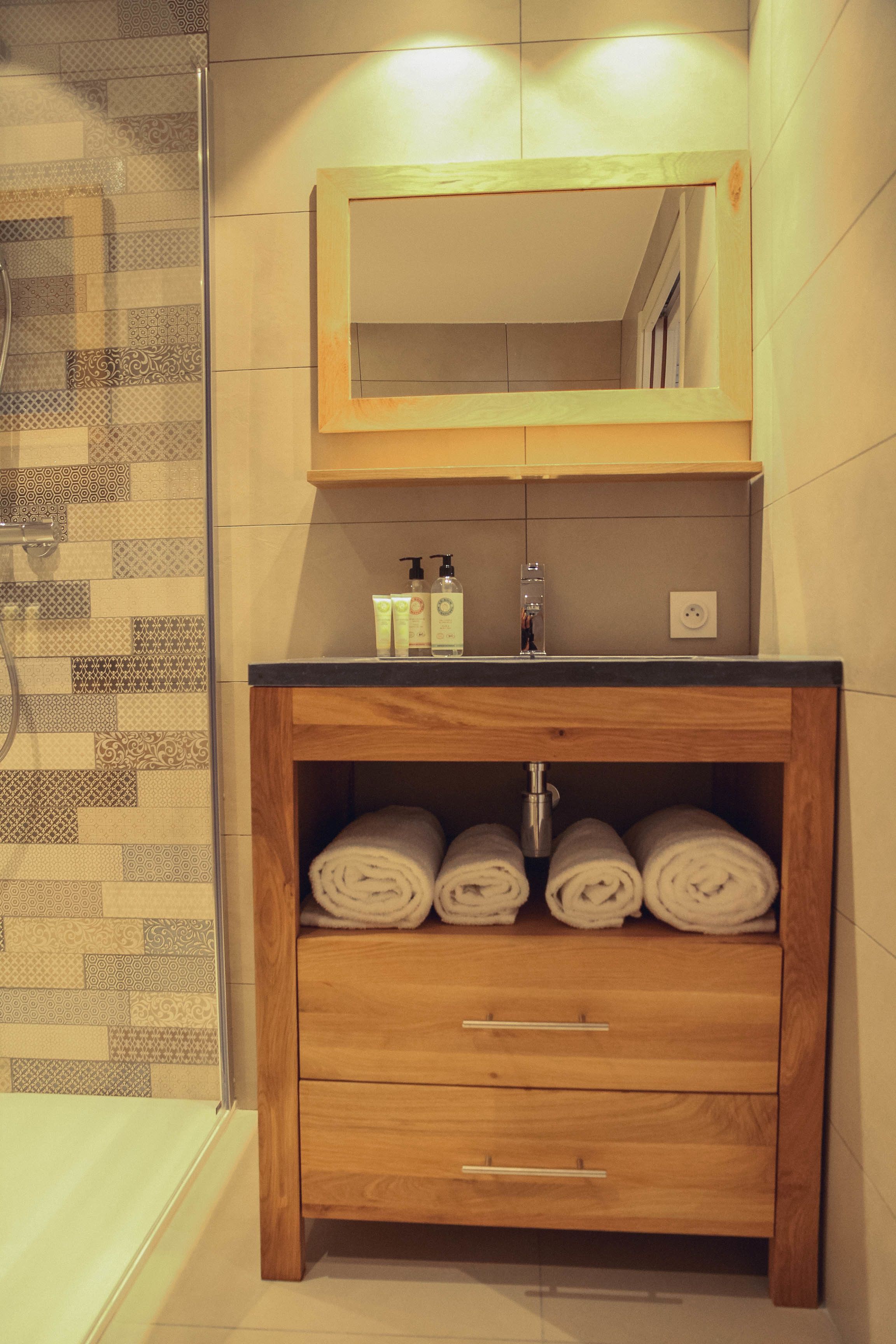 A bathroom with a wooden vanity, a mirror, a sink, and a towel rack.