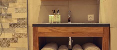 Un baño con tocador de madera, un espejo, un lavamanos y un perchero para toallas.