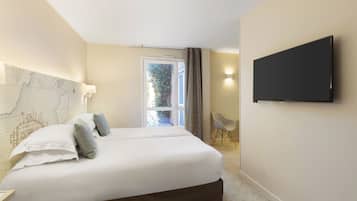 Una habitación de hotel con una cama grande, un televisor de pantalla plana en la pared y una ventana con cortinas.