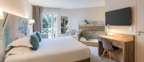 Habitación de hotel con una cama grande, un escritorio con silla, televisión y balcón con vista a zonas verdes.