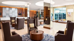 Een moderne lobby met zithoeken, een receptiebalie en uitzicht op het exterieur.