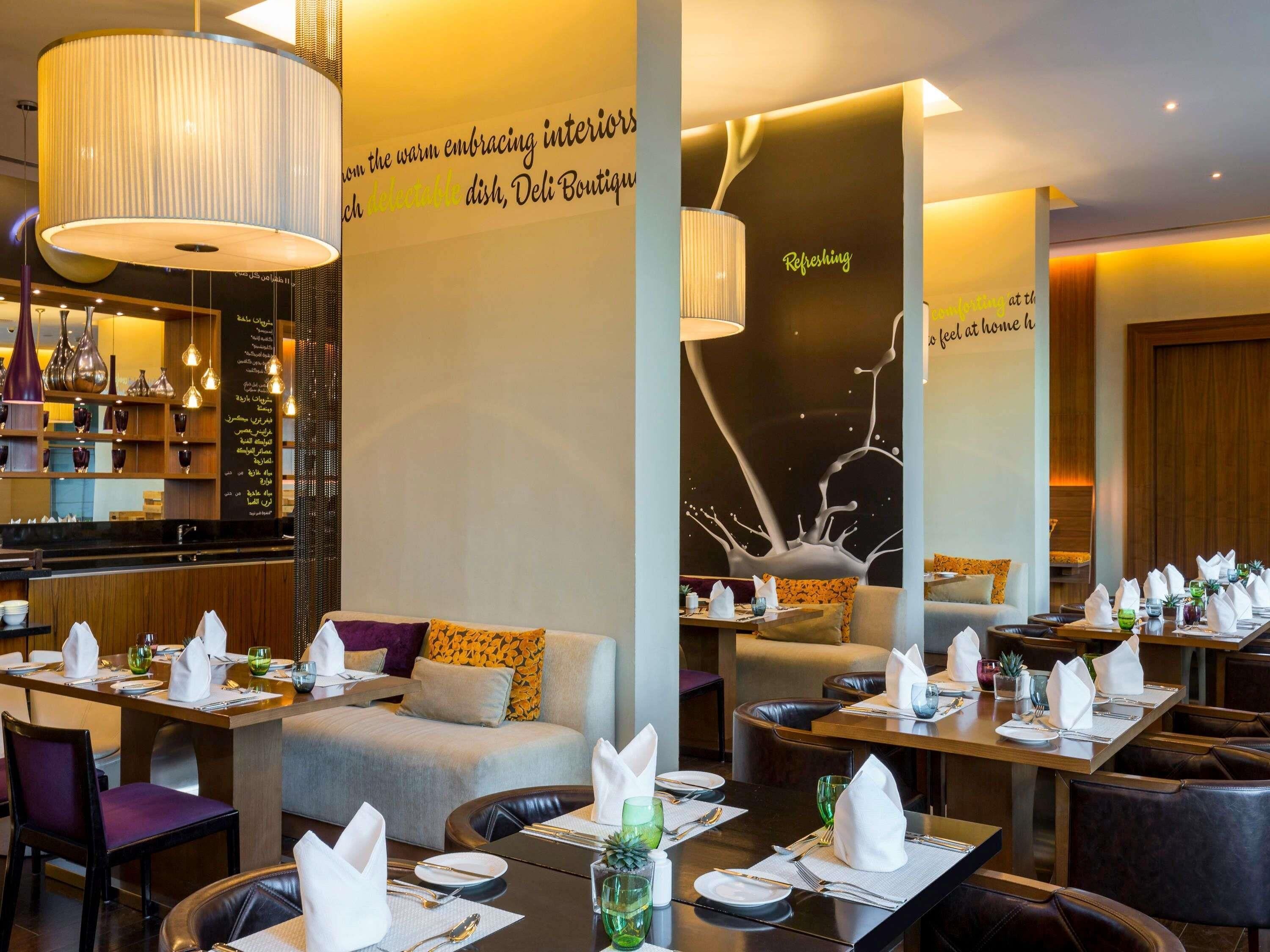 Un restaurante con mesas dispuestas para comer, una zona de bar y una pared con texto decorativo.