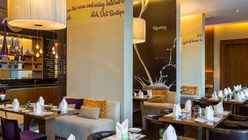 Un restaurante con mesas dispuestas para comer, una zona de bar y una pared con texto decorativo.