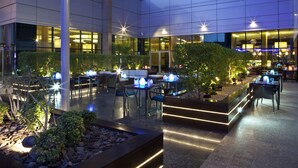 Een moderne hotel lobby met een ruime zithoek, een receptiebalie en een goed verlicht atrium.