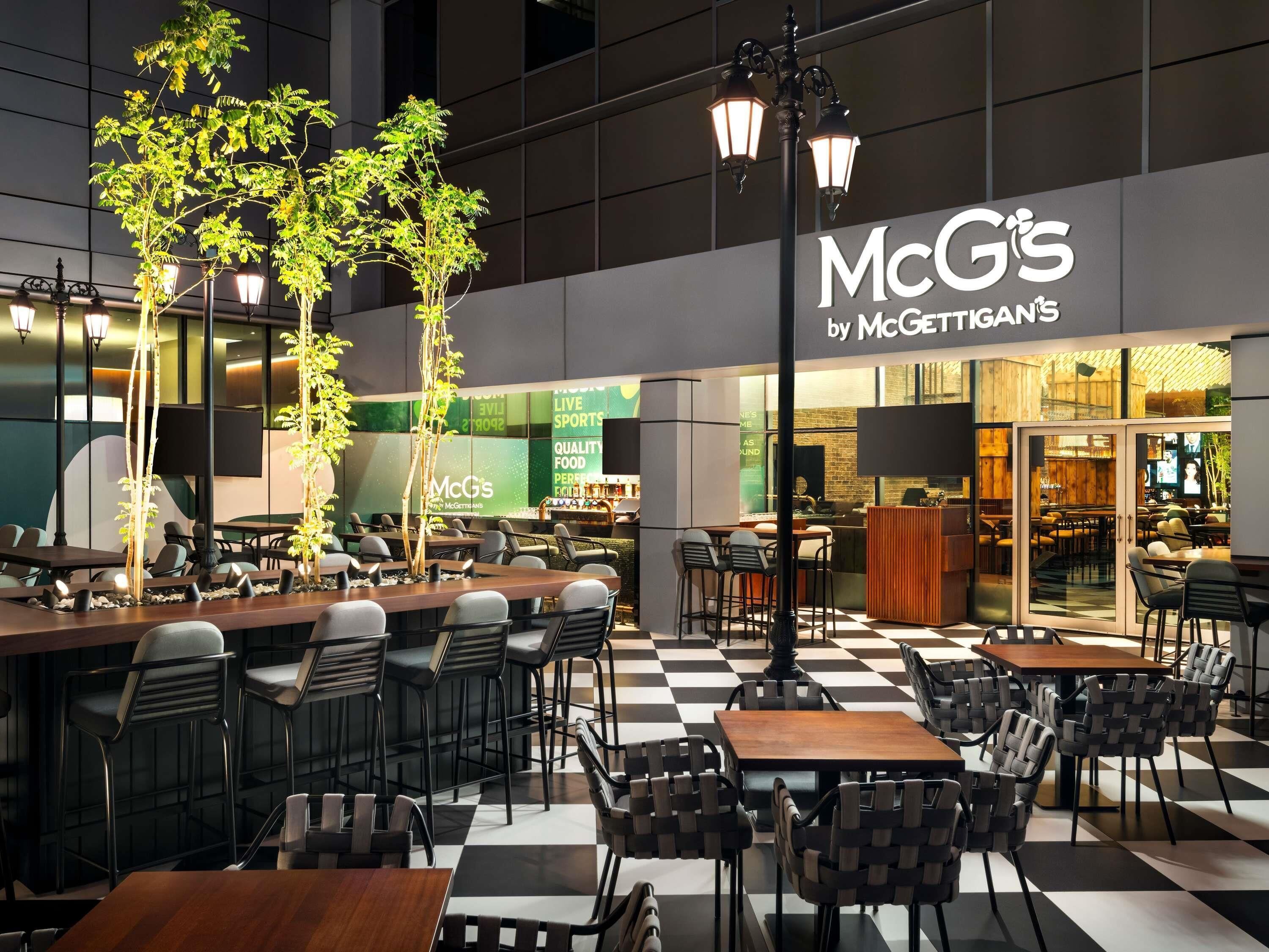 A McG's by McGettigan's restaurant with outdoor seating, tables, chairs, and decorative street lamps.
