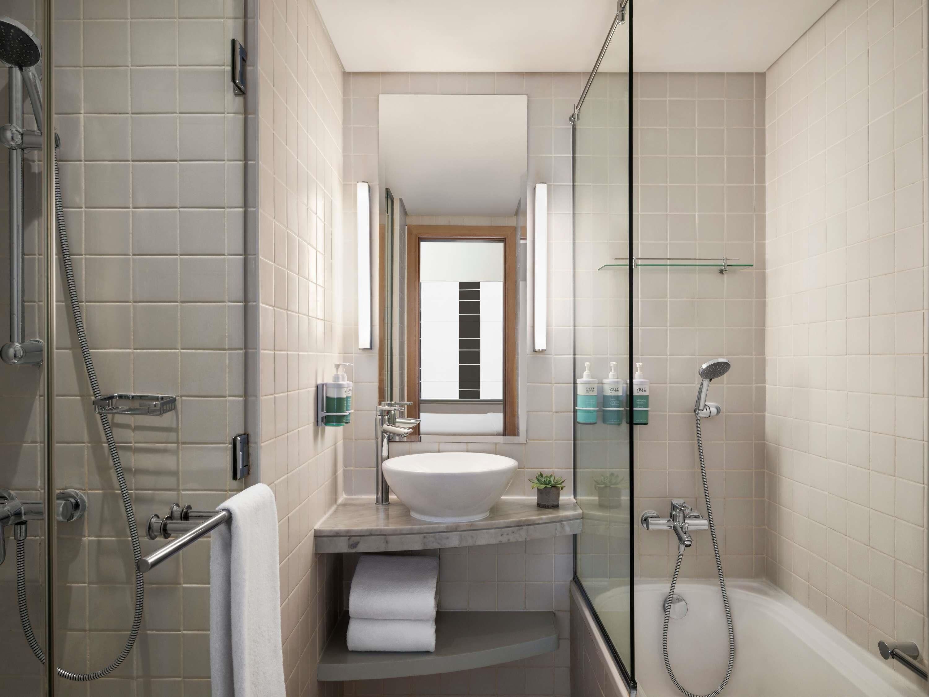 A modern bathroom with a glass-enclosed shower, a white sink, and a mirror above it.