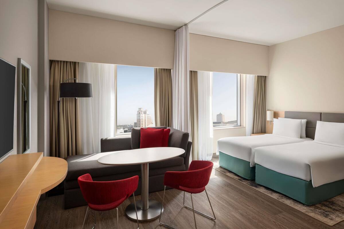 A hotel room with a bed, a sofa, a dining table, and chairs.